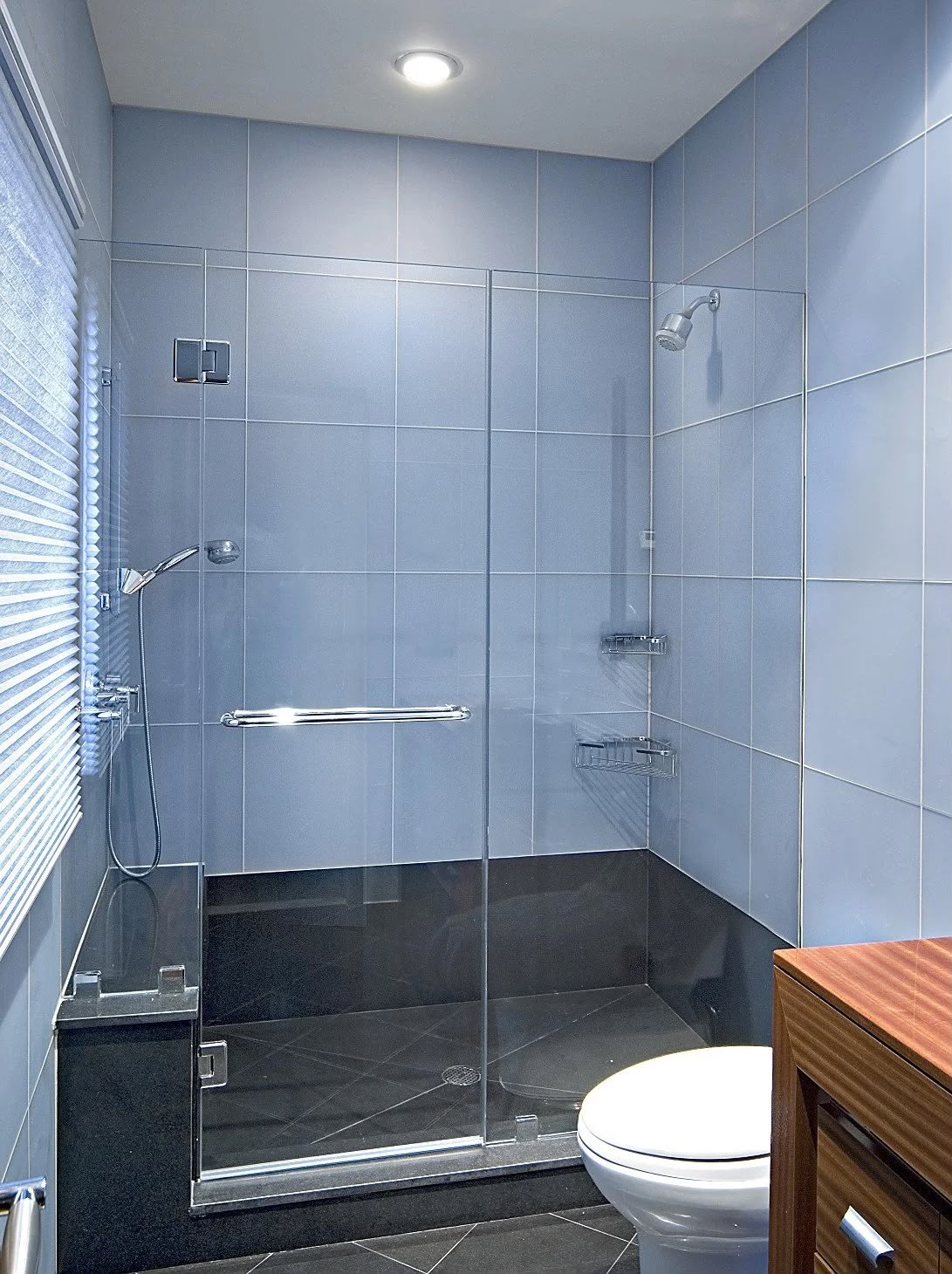 Blue tile bathroom with glass shower doors and dark floor