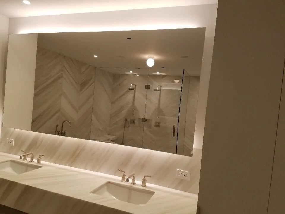 Double vanity bathroom with large frameless mirror and marble countertop