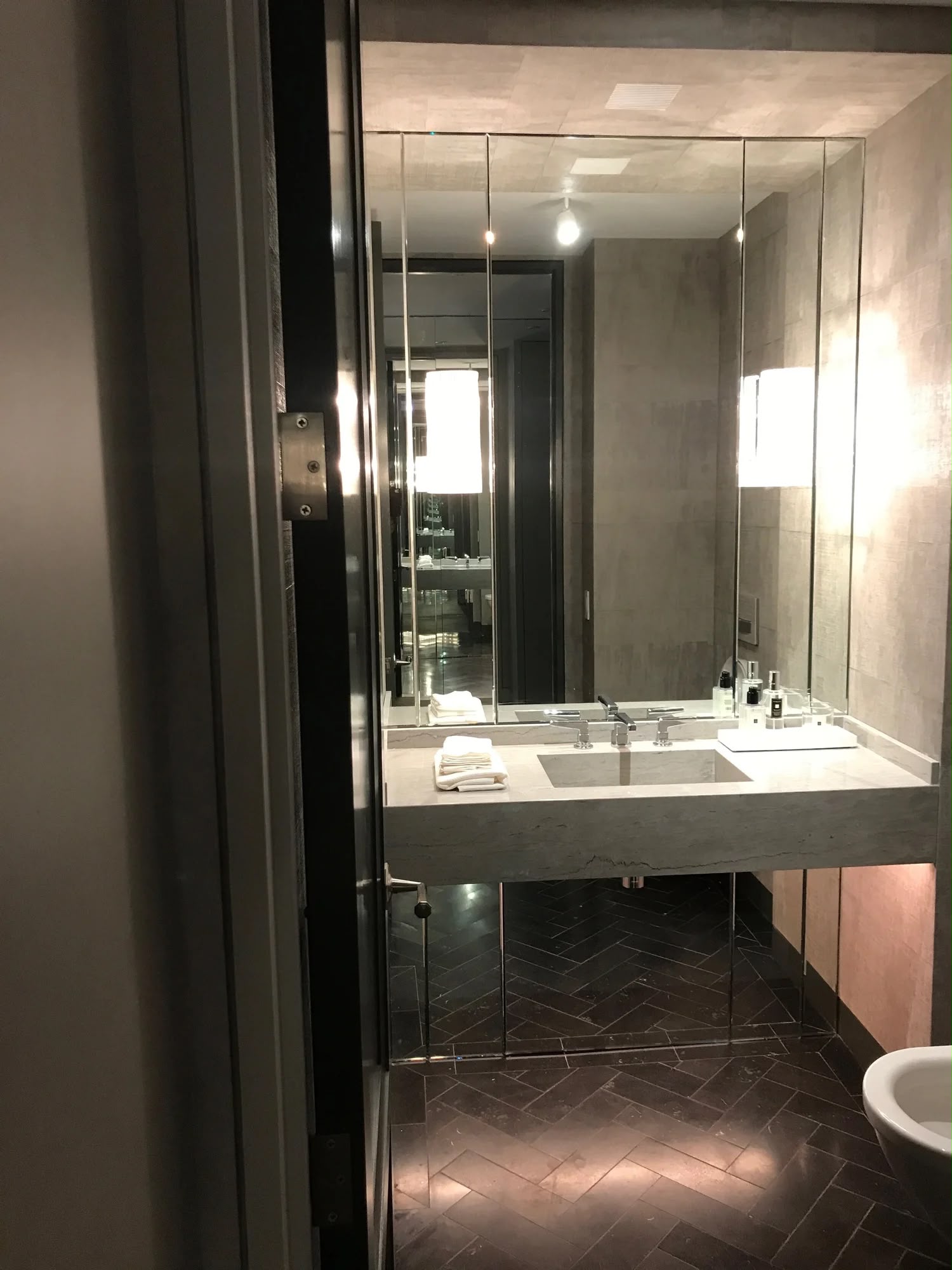 Dark luxury bathroom with pendant lighting and herringbone tile floor