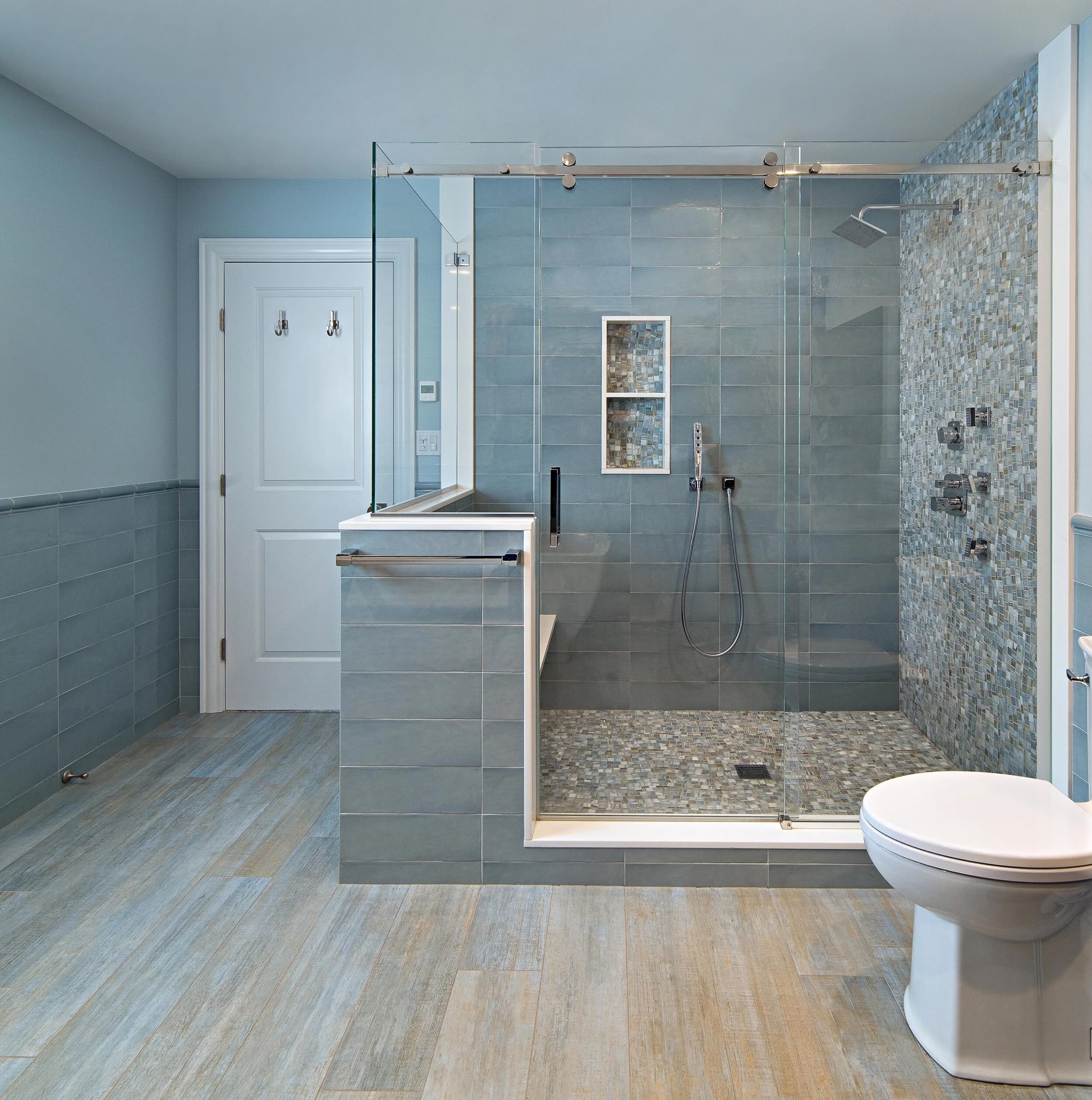 Elegant bathroom with blue tile walls and sliding glass shower door