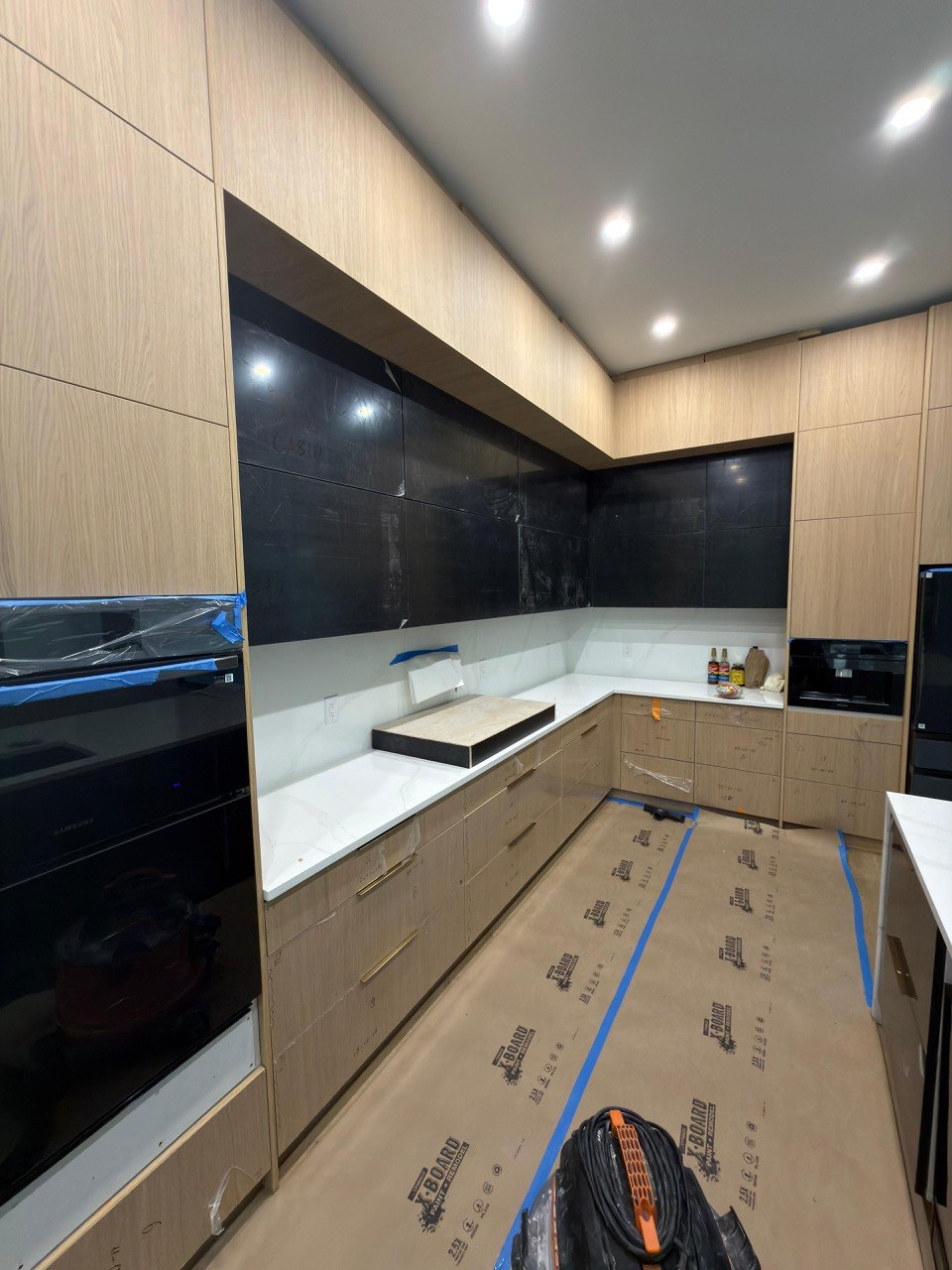 Modern kitchen with wood veneer cabinets and dark backsplash